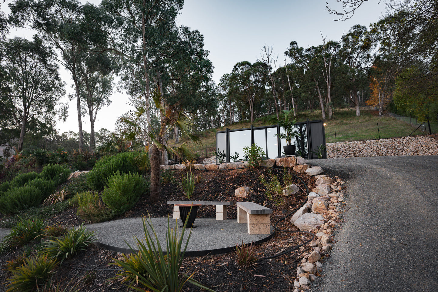 Off grid outdoor tiny home sculpture in a natural setting with trees and rocks.