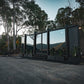 Modern modular tiny home in a forested area with mountains in the background