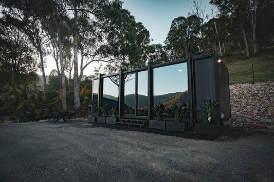 Modern modular tiny home in a forested area with mountains in the background