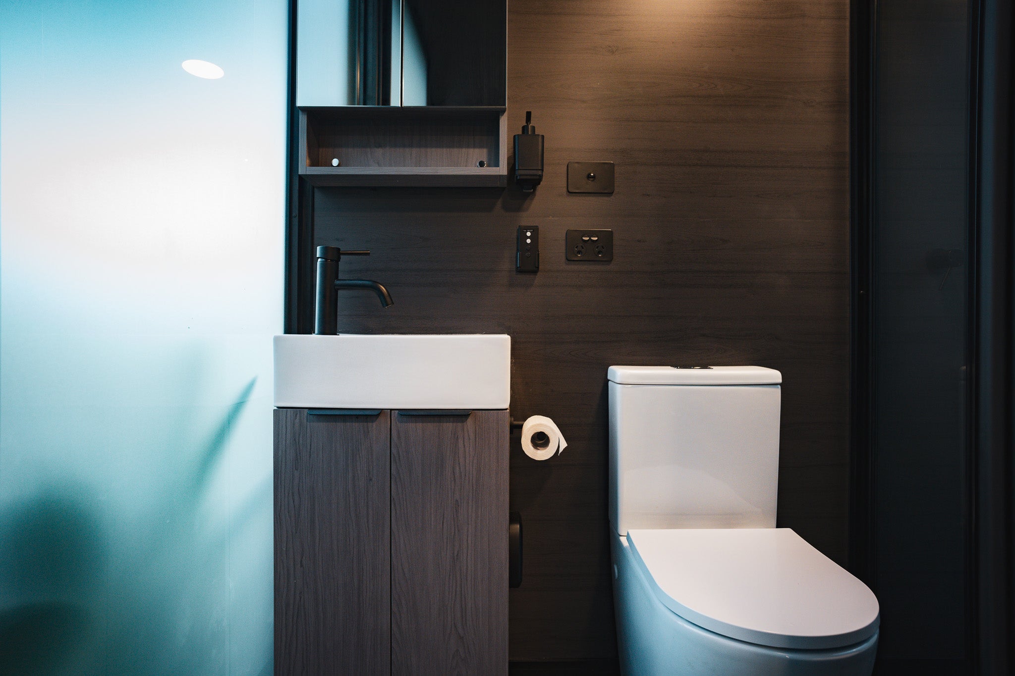 Bathroom of the Bright Elsewhere Pod featuring a modern vanity, matte black fittings, and soft natural light through frosted glass.