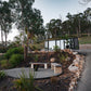 Off grid outdoor tiny home sculpture in a natural setting with trees and rocks.