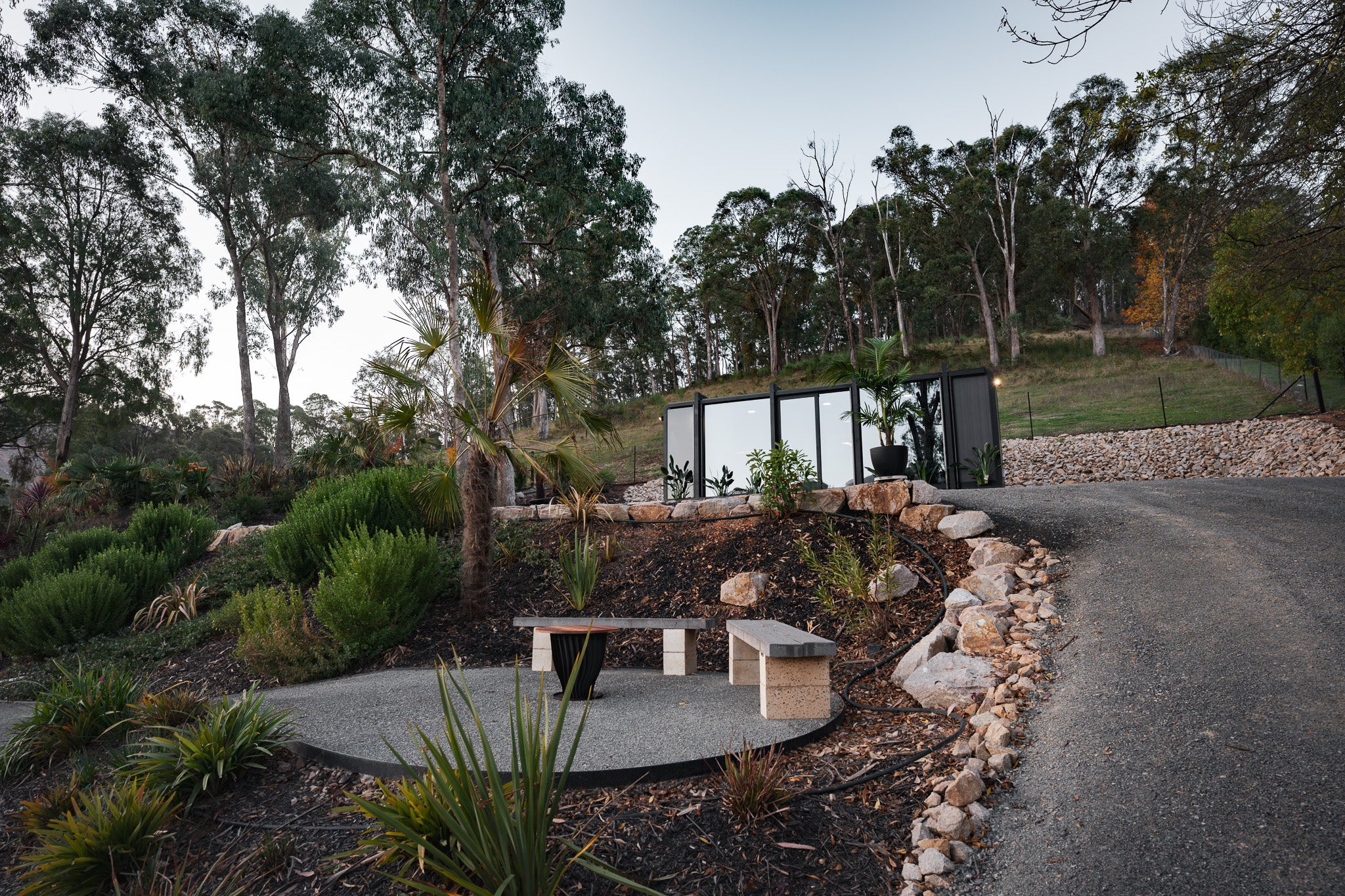 Exterior of the Bright Elsewhere Pod set among trees and landscaped gardens in Victoria’s alpine region, showcasing its minimalist black design.